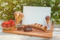 Card, chocolate ice cream, dark chocolate, basket of fresh strawberry and empty waffle cones near on rustic wooden table Royalty Free Stock Photo