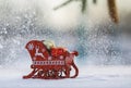 Card with Christmas sleigh with gifts in the forest under snowfall and spruce branch