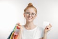 A happy redhair woman with shopping bags is holding business card