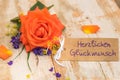 Card with german text, Herzlichen Glueckwunsch, means congratulation and orange colored rose flower
