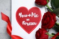 Card with love message near red roses on grey table, flat lay Royalty Free Stock Photo