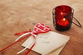 Card with Message With Love in the Letter, romantic candle holder with a candle and wooden red heart on a wooden table Royalty Free Stock Photo