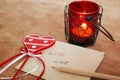 Card with Message With Love in the Letter, romantic candle holder with a candle and wooden red heart on a wooden table Royalty Free Stock Photo