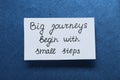 Card with phrase Big Journeys Begin With Small Steps on blue background, top view. Motivational quote Royalty Free Stock Photo
