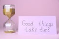 Card with phrase Good Things Take Time and sand clock on pink background. Motivational quote Royalty Free Stock Photo