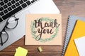 Card with phrase Thank You, laptop, glasses and notebooks on wooden table, flat lay