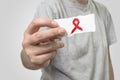 Card with red ribbon in hand to rise AIDS HIV awareness Royalty Free Stock Photo