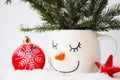Card snowy fir branches in a cup with the face of a sleeping snowman, a red Christmas ball and a star Royalty Free Stock Photo