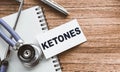 A card with text KETONES on wooden doctor`s table