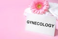 Card with word Gynecology, packed menstrual pads and flower on color background Royalty Free Stock Photo