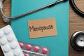 Card with word Menopause, book, pills and stethoscope on wooden table, flat lay