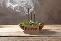 Card with word Retreat, green leaves and incense sticks on wooden table