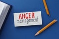 Card with words Anger Management, notebook and broken pencil on blue background, flat lay Royalty Free Stock Photo