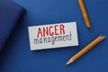 Card with words Anger Management, notebook and broken pencil on blue background, flat lay