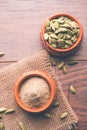 Cardamom powder or elaichi powder in bowl over moody background with pods. Royalty Free Stock Photo