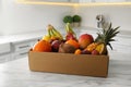 Cardboard box with assortment of exotic fruits on table in kitchen Royalty Free Stock Photo