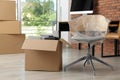 Cardboard box with belongings and packed chair in office