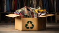 cardboard box filled with a jumble of old clothes, ranging from striped t-shirts to faded jeans and crumpled skirts. A r