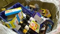 Cardboard box with glass bottles of alcohol, wine, canned products, spoiled food. Clutter, trash and scattered goods. Messy in