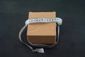 cardboard box with measuring tape on black wooden background Royalty Free Stock Photo