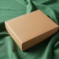 Cardboard box with a smooth texture sits on a draped green fabric. The box is Royalty Free Stock Photo
