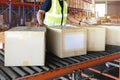 Cardboard boxes sorting on rollers conveyor belt. Worker moving boxes into storage warehouse Royalty Free Stock Photo