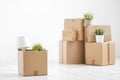 Cardboard boxes with things are stacked on the floor against the background of a white wall close up. Books and table