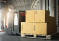 Cardboard boxes on Wooden Pallet with Worker Driving Electric Forklift Pallet Jack Unloading at The Warehouse. Package Boxes. Royalty Free Stock Photo