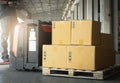 Cardboard boxes on Wooden Pallet with Worker Driving Electric Forklift Pallet Jack Unloading at The Warehouse. Storage Warehouse. Royalty Free Stock Photo