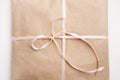 Cardboard carton package wrapped with light brown paper and tied with pink string ribbon in bow Royalty Free Stock Photo