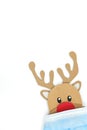 Cardboard cutout of Rudolph the red-nosed reindeer peeking while wearing a face mask. Covid during Christmas Royalty Free Stock Photo