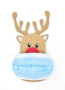 Cardboard cutout of Rudolph the red-nosed reindeer peeking while wearing a face mask. Covid during Christmas Royalty Free Stock Photo