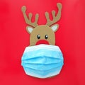 Cardboard cutout of Rudolph the red-nosed reindeer wearing a face mask. Covid during Christmas season concept. Royalty Free Stock Photo