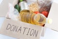 Cardboard donation box with food on white background close-up. Cereals, oil, canned food, vegetables in it. Donation and charity