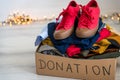 Cardboard donation box full with used clothes and shoes.