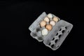 Cardboard egg box with seven eggs on black mat background