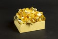 Cardboard gift box with decorative gold foil pieces inside and outside on black textured paper background
