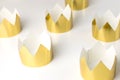 Cardboard golden crowns lying on a white table. Minimalistic style.