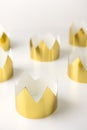 Cardboard golden crowns lying on a white table. Minimalistic style.