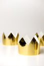 Cardboard golden crowns lying on a white table. Minimalistic style. Place for text. Copyspace.