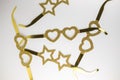 Cardboard golden eyeglasses in the shape of stars and hearts lying on a white table. Minimalistic style. Top view. Flat