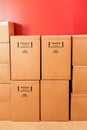 Cardboard moving boxes stacked up against a red wall