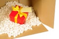 Cardboard packing box with red gift inside, polystyrene nuts, address label Royalty Free Stock Photo