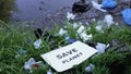 Cardboard with save planet phrase lying on open dumping near lake, recycling