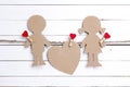 Cardboard silhouettes girl and boy with heart on white wooden ba