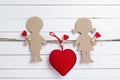 Cardboard silhouettes girl and boy with heart on white wooden ba