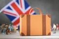 Cardboard suitcase, plastic toy people and a flag on an abstract background, a concept on the theme of moving or immigrating to Royalty Free Stock Photo