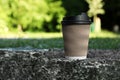 Cardboard takeaway coffee cup with plastic lid on stone surface outdoors, space for text Royalty Free Stock Photo
