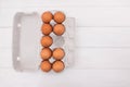 Cardboard tray with chicken eggs without one egg on a wooden background. View from above Royalty Free Stock Photo