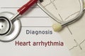 Cardiac diagnosis of Heart Arrhythmia. On doctor workplace are red stethoscope, printed on paper ECG line and a pen close-up lying Royalty Free Stock Photo